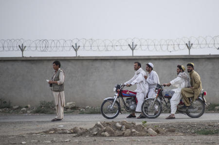 Afghans wait as ISAF personnel search a vehicle. 
Afghans commonly use motorcycles, as they provide a superior capability in the various terrains of the county.
Published by National Geographic.